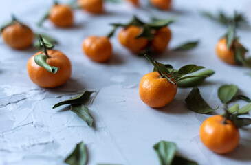 Fresh mandarin orange fruits or tangerines with leaves on a gray background or table, top view, copy space