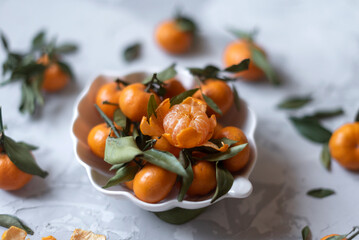 Fresh mandarin orange fruits or tangerines with leaves on a gray background or table in a white...
