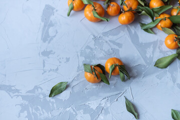 Fresh mandarin orange fruits or tangerines with leaves on a gray background or table, top view, copy space
