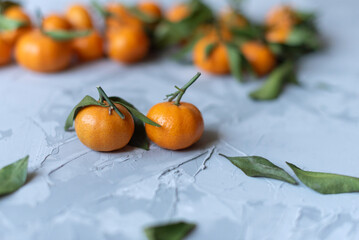 Fresh mandarin orange fruits or tangerines with leaves on a gray background or table