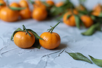 Fresh mandarin orange fruits or tangerines with leaves on a gray background or table