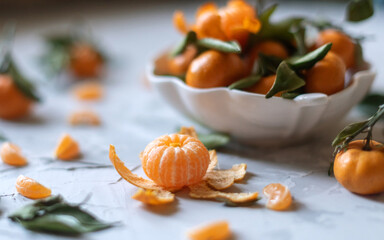 Fresh mandarin orange fruits or tangerines with leaves on a gray background or table in a white plate