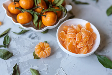 Fototapeta na wymiar Fresh mandarin orange fruits or tangerines with leaves on a gray background or table in a white plate