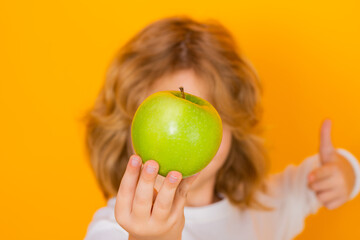 Kids face with fruits. Kid with apple in studio. Studio portrait of cute child hold apple isolated...