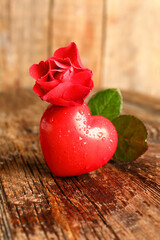 Fototapeta na wymiar Red heart with water drops and rose flower on wooden table. Valentines Day celebration