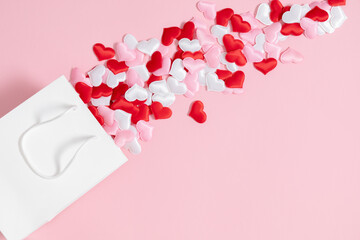 Valentine's Day concept. Paper white gift bag red and white confetti hearts on pink background. Valentine day, 8th march, Mother day background. Love concept. Flat lay, top view, copy space