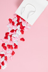 Valentine's Day concept. Paper white gift bag red and white confetti hearts on pink background. Valentine day, 8th march, Mother day background. Love concept. Flat lay, top view, copy space