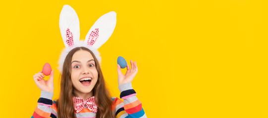 happy kid in bunny ears and bow tie hold easter eggs on yellow background. Easter child horizontal poster. Web banner header of bunny kid, copy space.