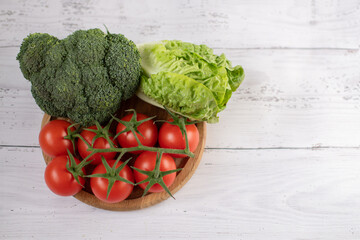 cabbage, tomatoes, broccoli on the table on a wooden salad bowl. White background