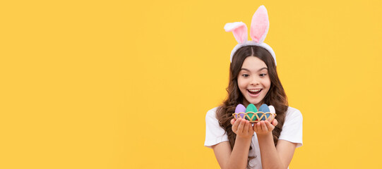 amazed kid in bunny ears hold eggs on yellow background. Easter child horizontal poster. Web banner...