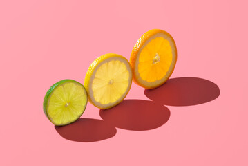 Citrus fruits variety, single slices isolated on a pink background.