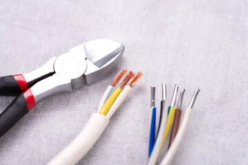 Electric cables without insulation and wire cutters on a gray table