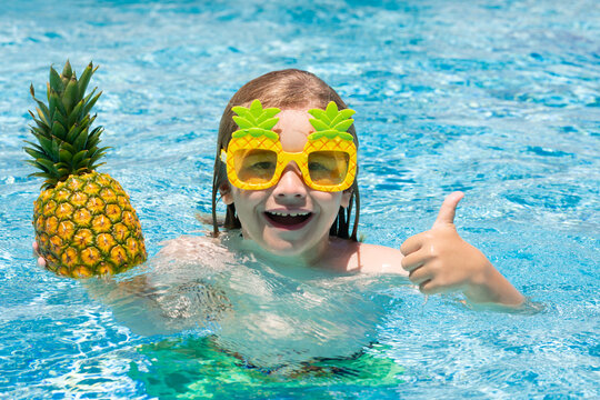 Funny little boy relaxing in a swimming pool, having fun during summer vacation in a tropical resort.
