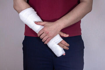 Broken arm, fingers. A white man in a red T-shirt with a cast on his arm.