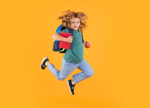 Full length body of little school kid jumping having fun isolated yellow color background. Crazy school boy jump.