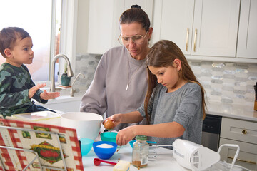 Obraz premium A mother is baking in the kitchen with her young son and daughter