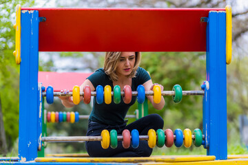 Young woman at the playground with toy educational abacus. Background