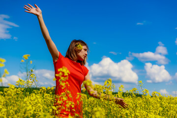 Young pretty woman in a colored dress on Lightning cheerful yellow background blooming rapeseed...