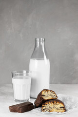 buns with poppy seeds in chocolate with a bottle of milk and a glass close-up on a gray background