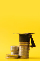 Graduated cap with coins on yellow background. Savings for education concept