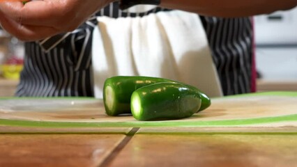 Woman cutting jalapeno pepper in kitchen