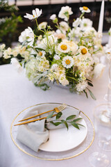 Banquet table decorated with plates, cutlery, candles, glasses and flower arrangements