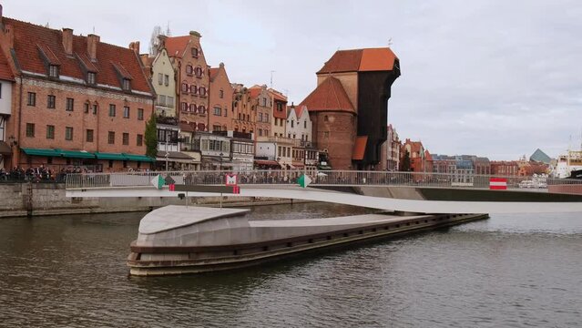 New modern bridge turning in Old town in Gdansk reflection in Moltawa River Cityscape. Ancient crane. Opening of revolving footbridge, Granary Island Visit Gdansk Poland Travel destination. Tourist
