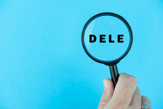 Focused on DELE exam. Word DELE (Diploma de Espa&ntilde;ol como Lengua Extranjera) under magnifying glass. Spanish Language Proficiency Test. Test Preparation. E-learning.