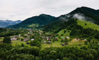 Traditional ukrainian houses in mountain village .  Rural landscape with buildings, trees .
