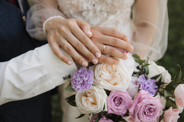 Obraz na płótnie Canvas close-up of the hands of the newlyweds with rings on the background of a bouquet
