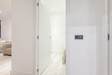White walls of a hallway with a wooden door leading to a bedroom