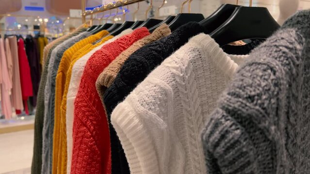 Women's knitted woolen pullovers hang on hangers in a clothing store