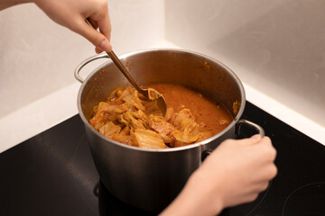 Cooking kimchi stew with a pot, stir the spicy stew with a spoon