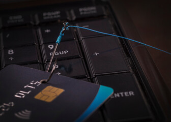 soft focus. close-up. bank card. the keyboard is black. a fishing hook. concept. stealing money on...