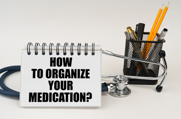 On the table are office supplies, a stethoscope and a notepad with the inscription - How to organize your medication