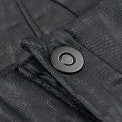 Metal fastener on avant-garde black waxed pants