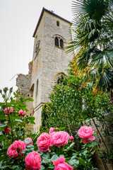 Fototapeta na wymiar Pink roses and medieval tower of the collegiate church of La Romieu in the south of France (Gers)
