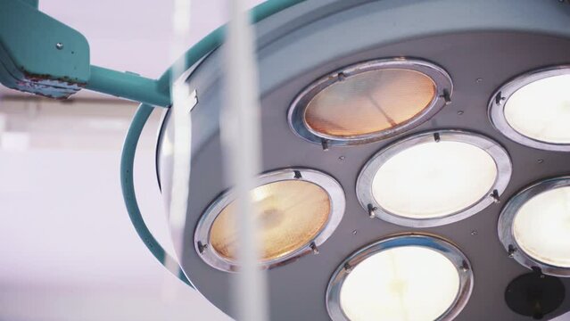 Surgical light equipment on ceiling wall in operating room. Medical modern technical stuff. Bright white lamp. Emergency resuscitation concept. Closeup detail. Covid-19, corona virus effects. Nobody