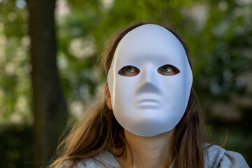 woman with full face white mask sitting in the woods