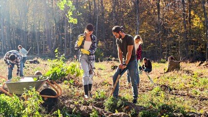 Caucasian people coworking together in park as eco activists and planting seedlings of trees on...