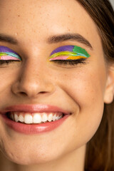 Cropped view of freckled teenage girl with colorful makeup.
