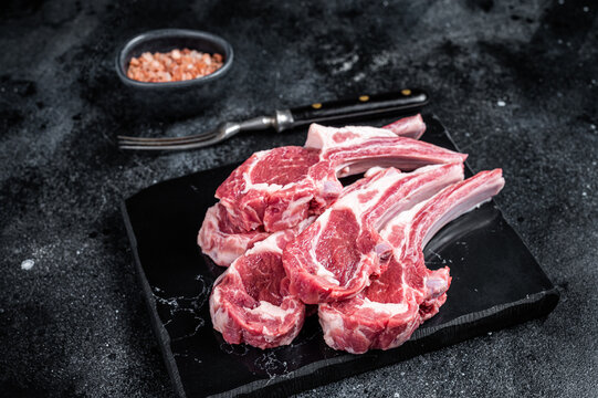 Uncooked lamb mutton chops, raw meat steaks. Black background. Top view