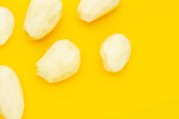 Raw peeled potatoes on yellow background