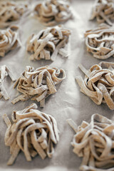Homemade pasta. Dry fettuccine noodles in nests on baking tray close up. Making whole-grain pasta