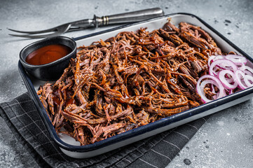 Pulled beef meat with hot chili sauce in baking dish. Gray background. Top view