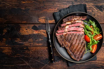 Fotobehang Barbecue grilled and sliced wagyu Rib Eye beef meat steak on a plate. Dark background. Top view. Copy space © Vladimir