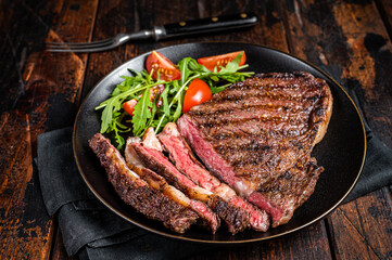 Barbecue grilled and sliced wagyu Rib Eye beef meat steak on a plate. Dark background. Top view