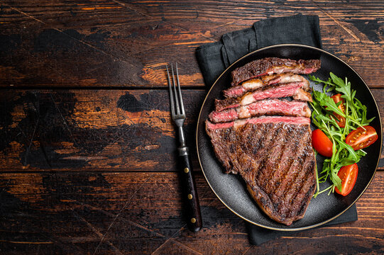Barbecue grilled and sliced wagyu Rib Eye beef meat steak on a plate. Dark background. Top view. Copy space
