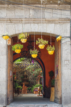 Mexico City, Mexico - A dark red arched doorframe into a courtyard with decorations hanging in it, in the neighbourhood of San Angel, Mexico City.  Image has copy space.