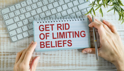 Get Rid Of Limiting Beliefs text in hands on wood table, on white paper